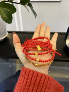 Bàn tay đeo vòng chỉ đỏ, ánh sáng huyền ảo.