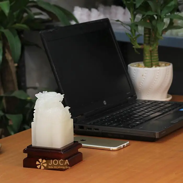 Bàn tay đặt vật phẩm phong thủy trên bàn làm việc.