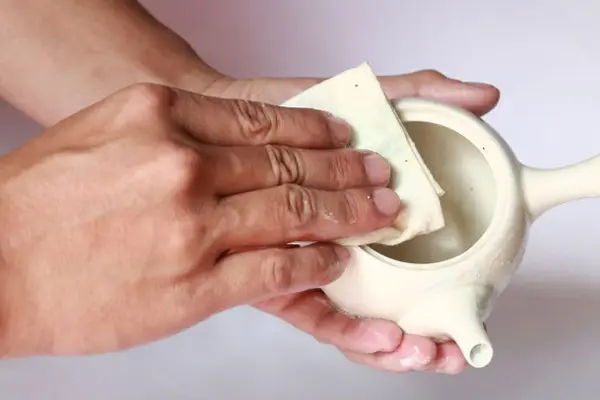 Hóa giải bếp bằng muối: Cẩm nang chuyên sâu và chính xác 6 Bàn tay rắc muối vào gốm sứ.