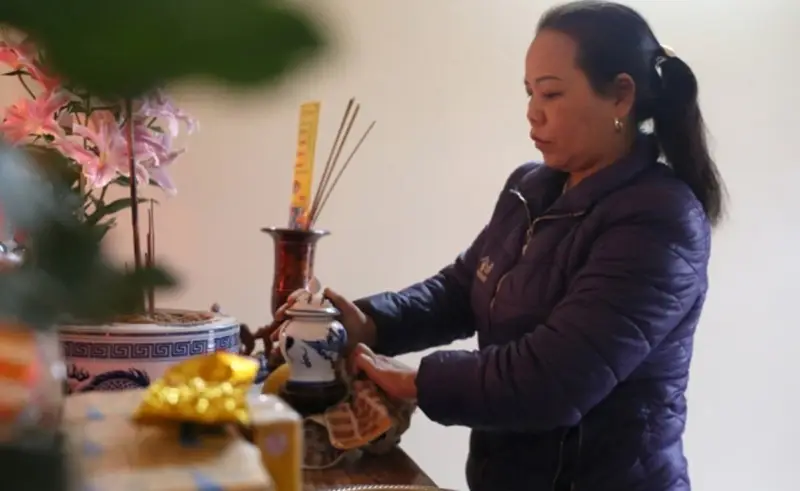 Người phụ nữ thành tâm lau dọn bàn thờ.