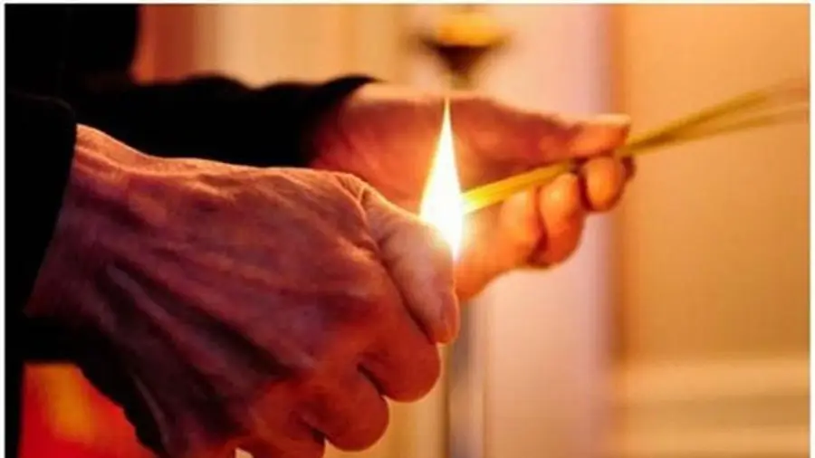 Bàn tay thắp hương thành kính trước bàn thờ.