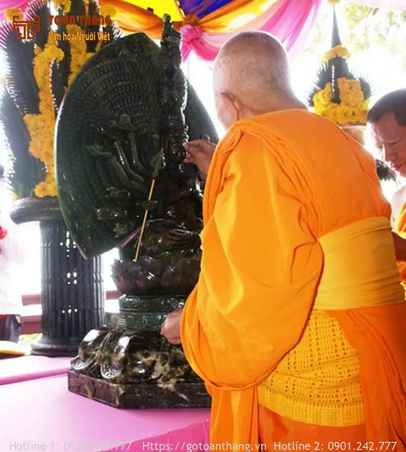 Hình ảnh một tay đang thực hiện nghi thức khai quang điểm nhãn trên một vật phẩm phong thủy, có khói