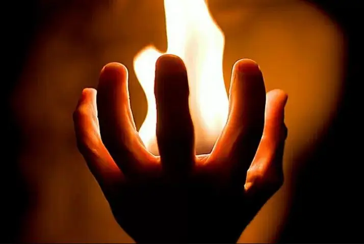 Tay cố gắng dập tắt ngọn lửa nhỏ.