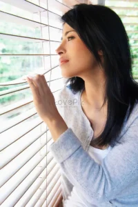 Phụ nữ suy tư nhìn ra cửa sổ mờ ảo.