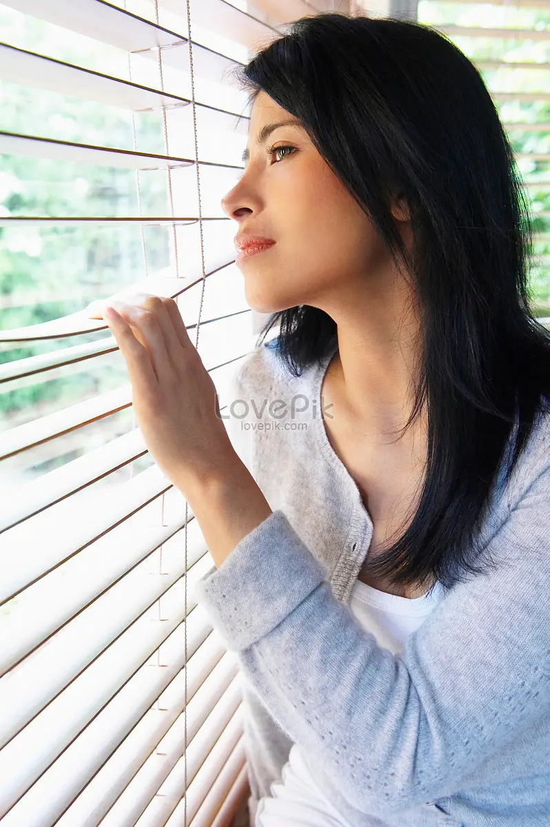 Phụ nữ suy tư nhìn ra cửa sổ mờ ảo.