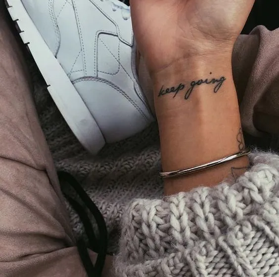 Hình xăm chữ tiếng Anh "Keep going" trên cổ tay, biểu thị sự kiên trì