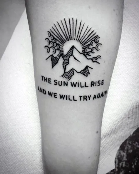 Hình xăm chữ tiếng Anh "The sun will rise and we will try again" trên vai, biểu tượng của sự tái sinh