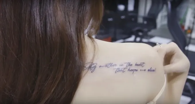 Hình xăm chữ tiếng Anh "My mother is the heart that keeps me alive" trên cánh tay, thể hiện lòng biết ơn mẹ