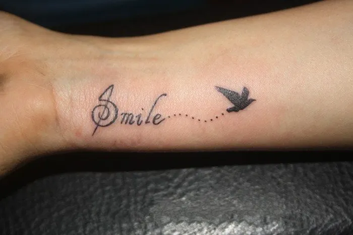 Hình xăm chữ tiếng Anh "Smile" trên ngón tay, biểu thị sự lạc quan