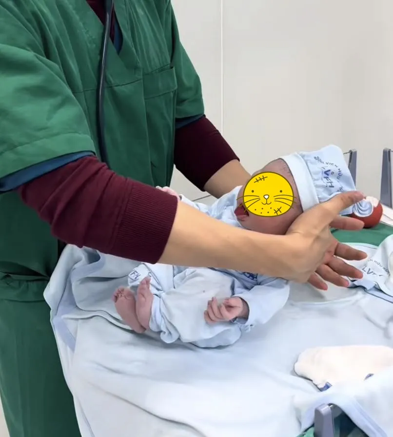 Y tá đang bế em bé trong phòng kiểm tra sơ sinh