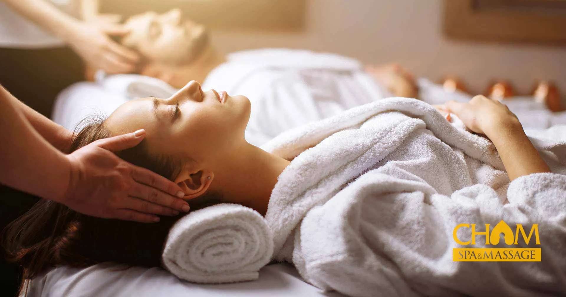 Cận cảnh nhân viên chuẩn bị phòng massage với ánh sáng dịu nhẹ tại cơ sở The Grand Spa